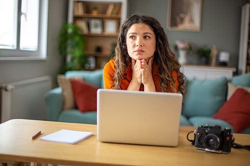 Bekymret kvinde foran computer i stue
