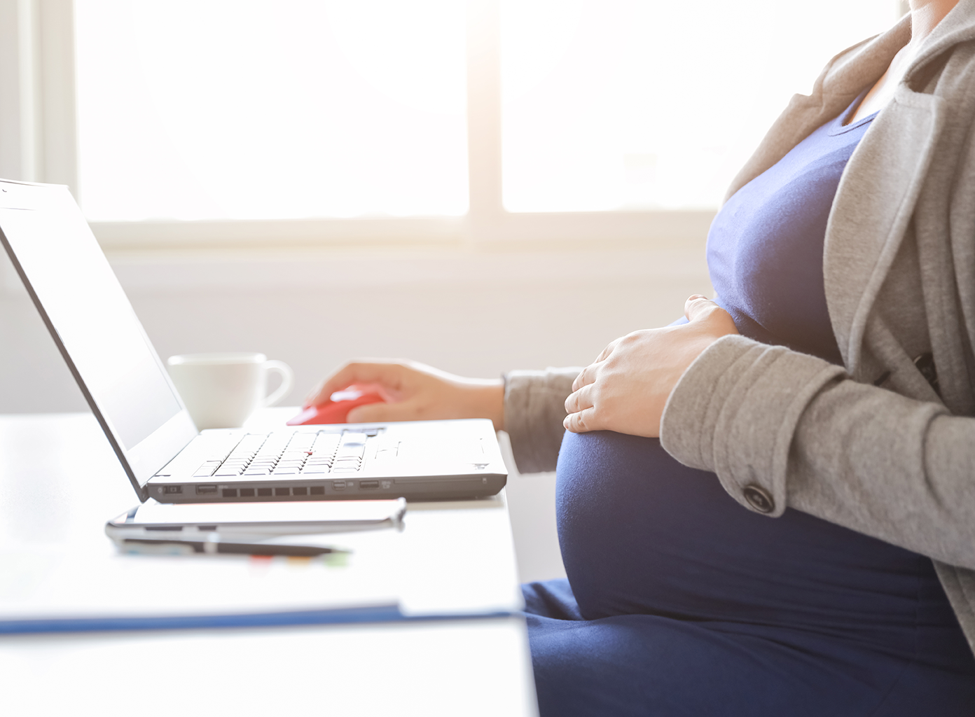 Dame med gravid mave siddende ved en computer
