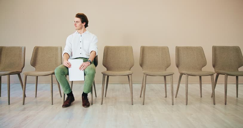 Mand, sidder alene på stol, iblandt flere tomme stole